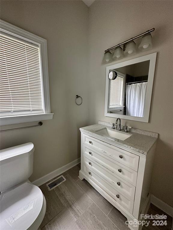 bathroom featuring a shower with curtain, plenty of natural light, vanity, and toilet