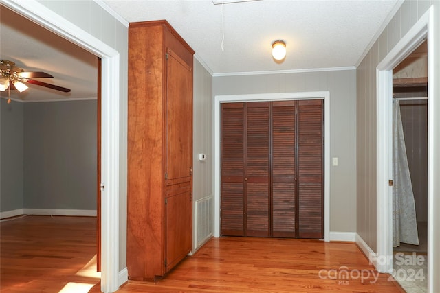 hall featuring ornamental molding, a textured ceiling, and light wood-type flooring