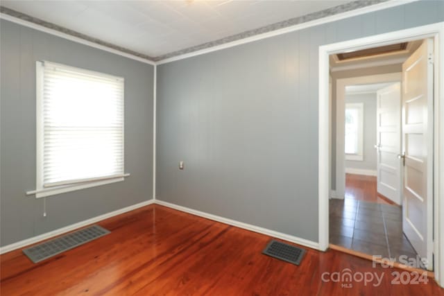 unfurnished room featuring crown molding and dark wood-type flooring