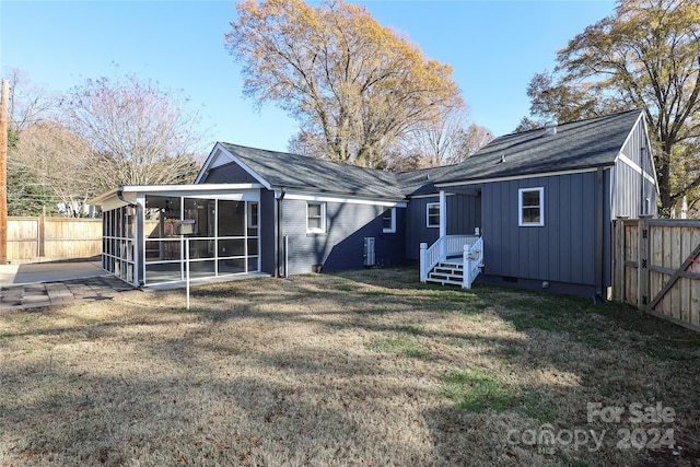 back of property with a sunroom and a yard