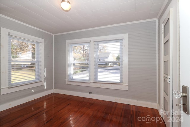 empty room featuring wood-type flooring and crown molding