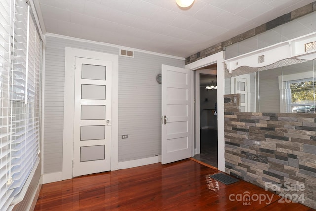 unfurnished room with dark hardwood / wood-style floors, crown molding, and a notable chandelier