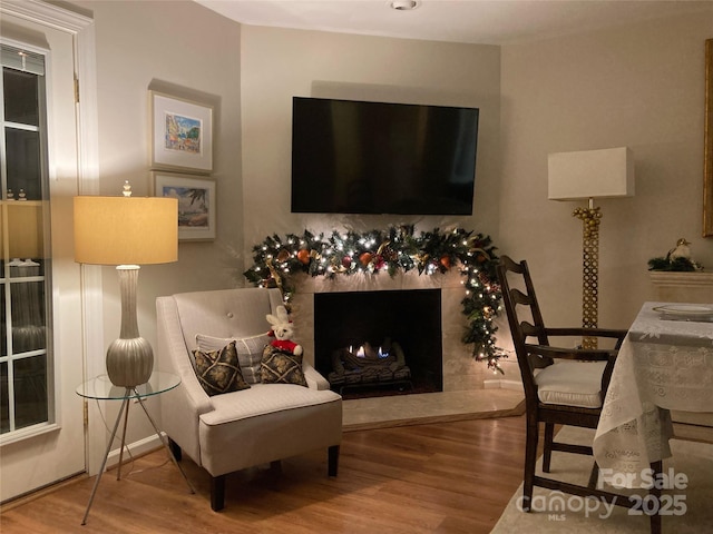 living area with a tiled fireplace and hardwood / wood-style flooring