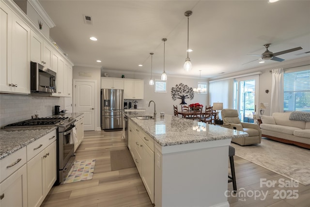 kitchen with white cabinetry, a center island with sink, light hardwood / wood-style floors, and appliances with stainless steel finishes