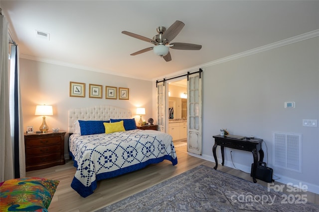 bedroom featuring light wood-type flooring, ensuite bathroom, ceiling fan, and crown molding