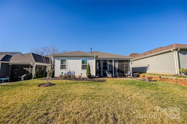 rear view of house featuring a lawn and a sunroom