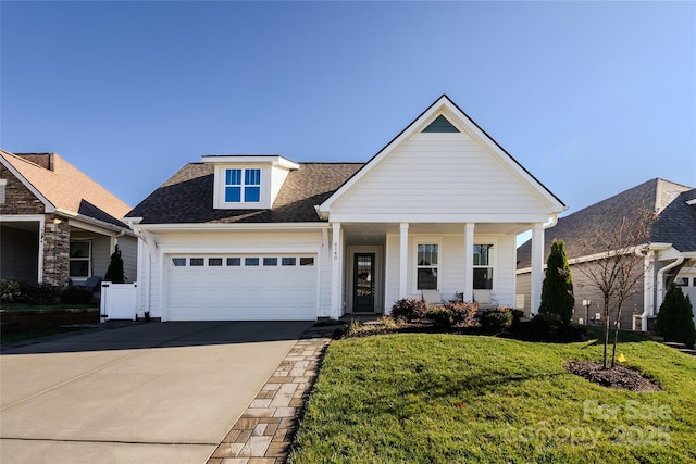 view of front of house featuring covered porch, a front yard, and a garage