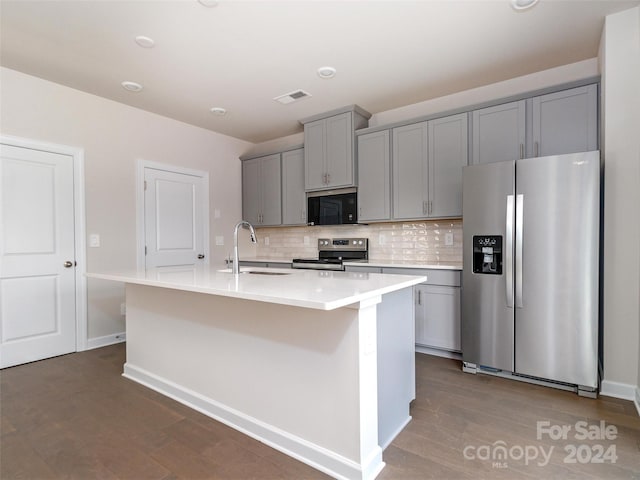 kitchen with gray cabinetry, sink, a kitchen island with sink, stainless steel appliances, and decorative backsplash