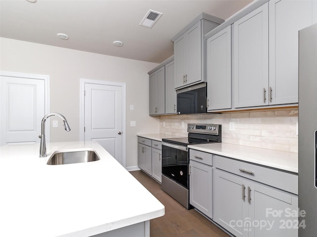 kitchen featuring gray cabinetry, sink, dark wood-type flooring, backsplash, and appliances with stainless steel finishes