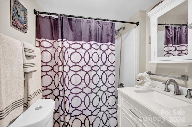 bathroom featuring curtained shower, vanity, and toilet