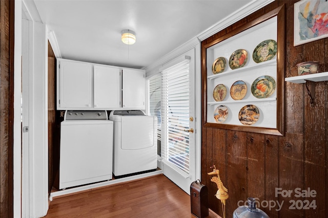 clothes washing area featuring cabinets, crown molding, washer and clothes dryer, and dark wood-type flooring