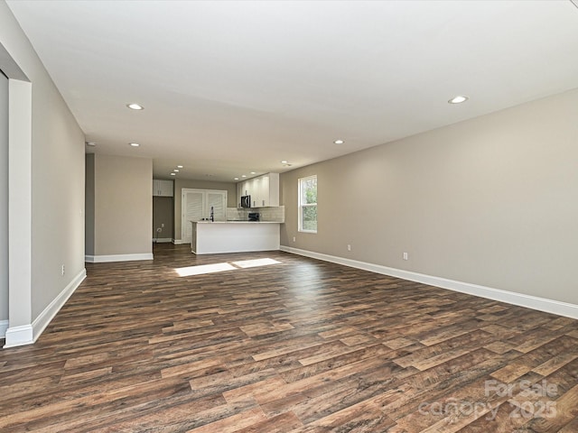 unfurnished living room with baseboards, dark wood-type flooring, and recessed lighting