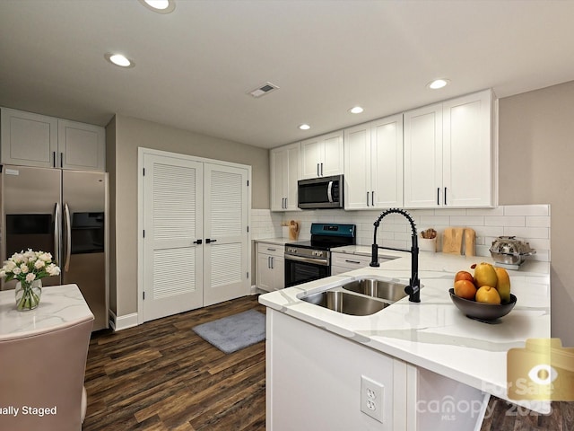 kitchen featuring visible vents, a peninsula, stainless steel appliances, white cabinetry, and a sink