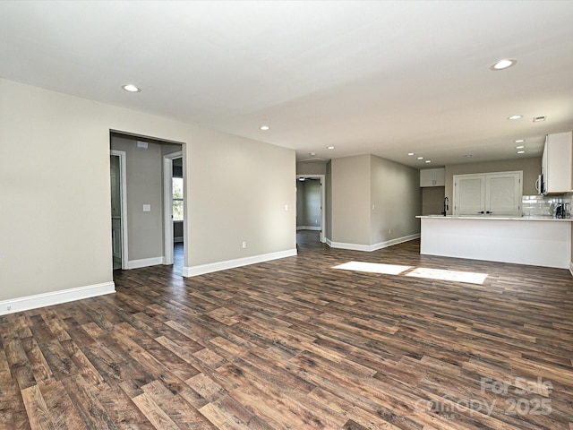 unfurnished living room featuring dark wood-style flooring, recessed lighting, and baseboards