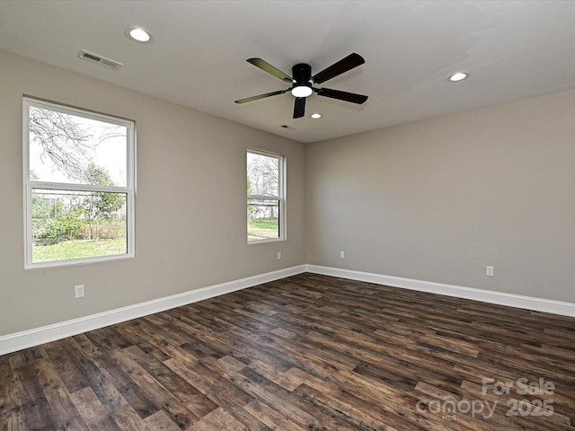 spare room with baseboards, dark wood-type flooring, visible vents, and recessed lighting