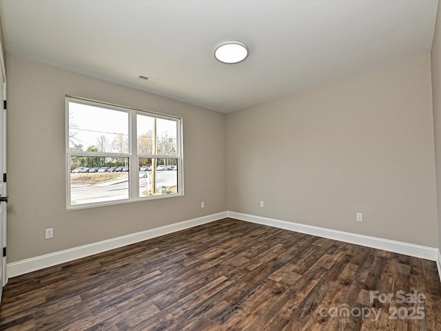 unfurnished room with dark wood-style flooring, visible vents, and baseboards