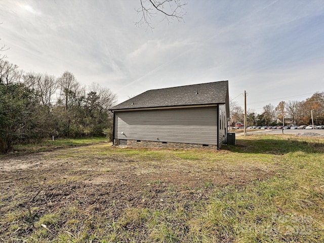 exterior space with a shingled roof, crawl space, and a yard