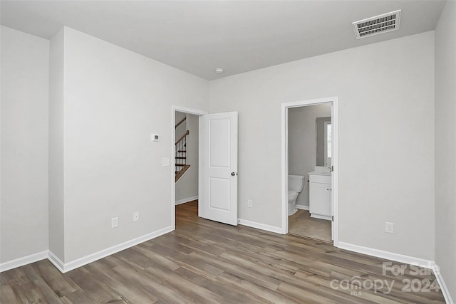 unfurnished bedroom with wood-type flooring and ensuite bathroom