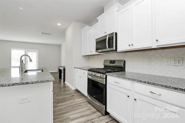 kitchen featuring white cabinets, light stone countertops, sink, and appliances with stainless steel finishes