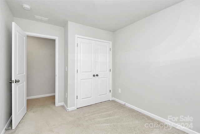 unfurnished bedroom with light carpet and a closet