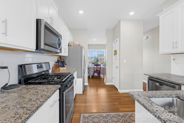 kitchen featuring white cabinetry, light stone countertops, dark wood-type flooring, and stainless steel appliances