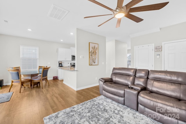 living room featuring ceiling fan and light hardwood / wood-style floors