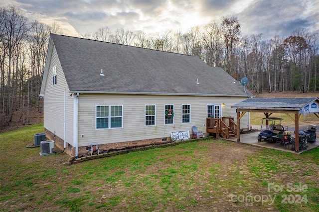 rear view of house featuring central AC, a yard, and a carport