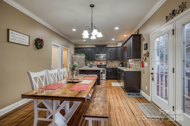 kitchen with ornamental molding, stainless steel appliances, and light hardwood / wood-style floors