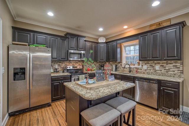 kitchen featuring sink, a center island, stainless steel appliances, light hardwood / wood-style flooring, and a kitchen bar