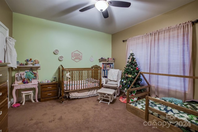 carpeted bedroom featuring ceiling fan and a nursery area