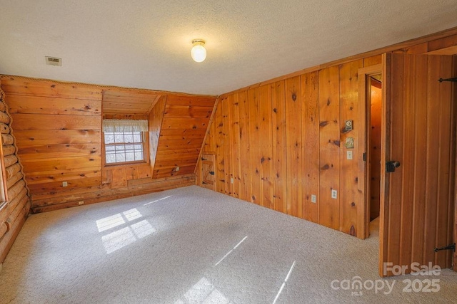 spare room with carpet floors, wooden walls, and a textured ceiling