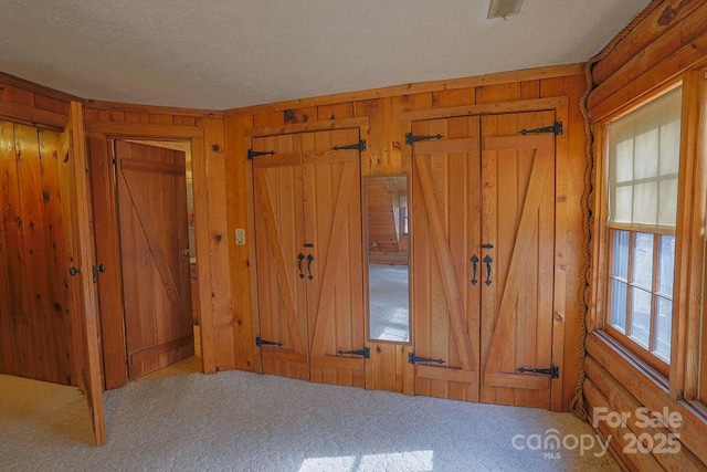 unfurnished bedroom with wooden walls, carpet flooring, and a textured ceiling