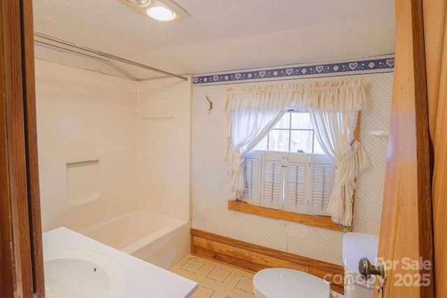 full bathroom with shower / tub combination, sink, a textured ceiling, and toilet