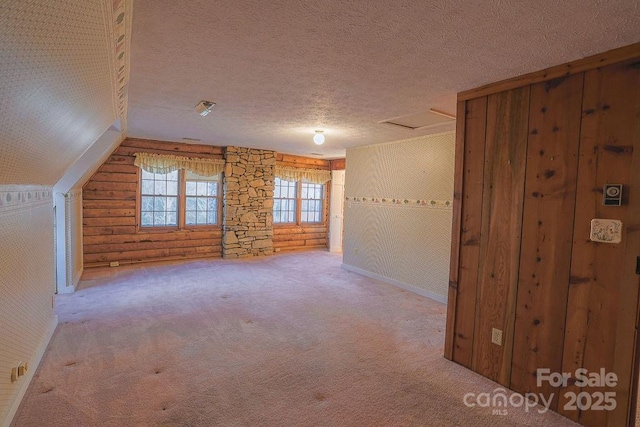 additional living space featuring vaulted ceiling, carpet, and a textured ceiling