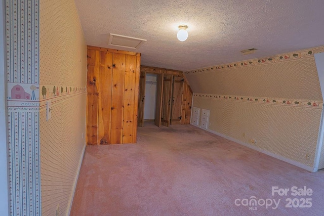 additional living space featuring vaulted ceiling, a textured ceiling, and carpet