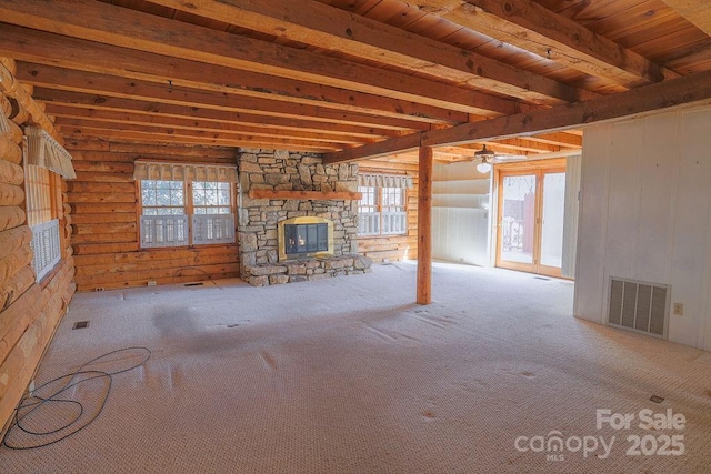 unfurnished living room with beamed ceiling, a fireplace, rustic walls, and light carpet