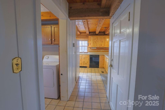 interior space featuring light tile patterned floors, wood ceiling, beam ceiling, black dishwasher, and washer / clothes dryer