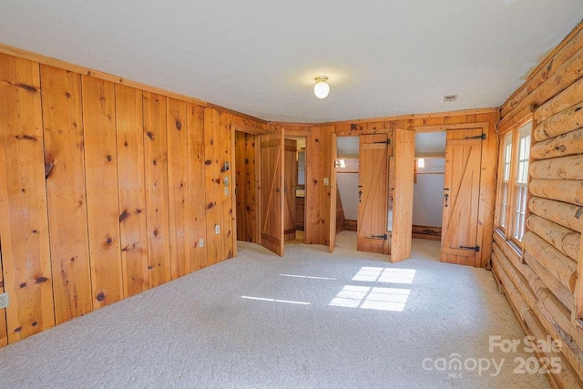 empty room featuring rustic walls, wooden walls, and carpet
