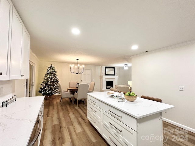 kitchen with hardwood / wood-style floors, a center island, white cabinetry, and crown molding