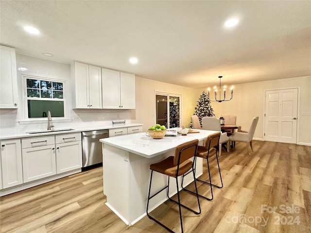 kitchen with white cabinets, decorative light fixtures, stainless steel dishwasher, and a kitchen island