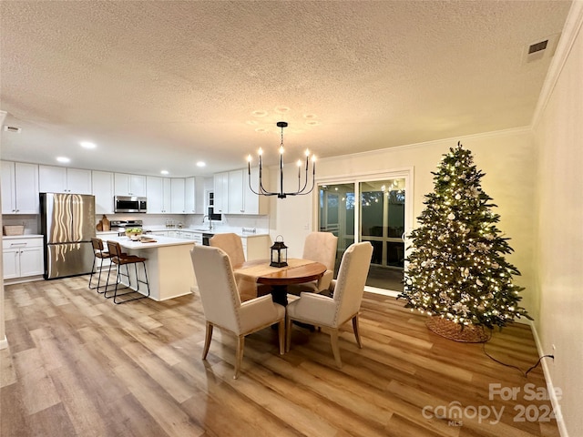 dining room featuring a notable chandelier, ornamental molding, a textured ceiling, and light hardwood / wood-style flooring