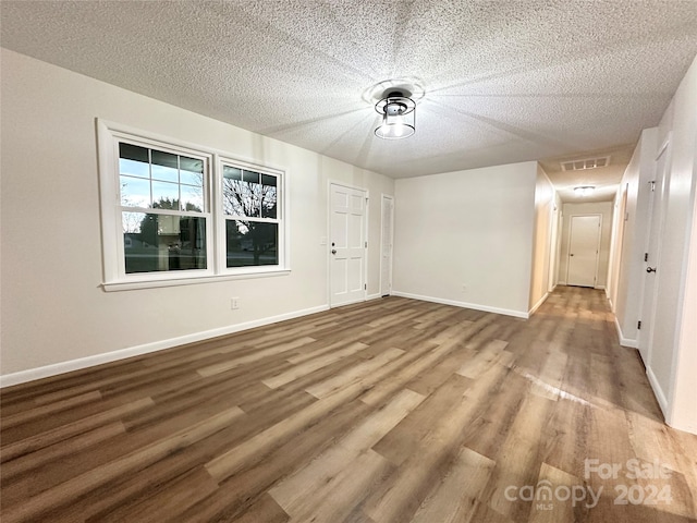 unfurnished room with a textured ceiling and light wood-type flooring