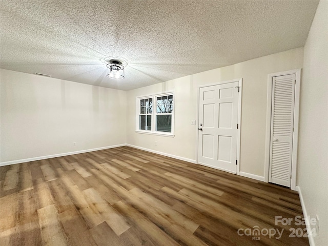 empty room with wood-type flooring and a textured ceiling