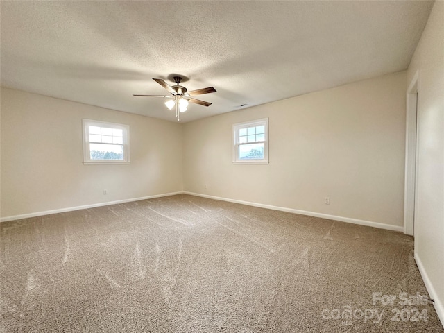 carpeted empty room featuring a textured ceiling, ceiling fan, and a healthy amount of sunlight