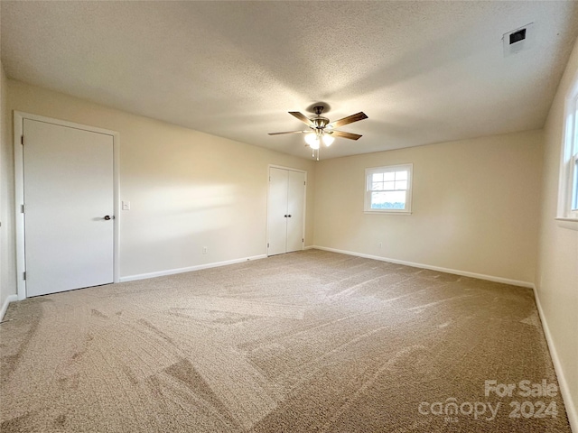 carpeted empty room featuring ceiling fan and a textured ceiling