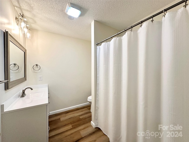 bathroom featuring vanity, a textured ceiling, hardwood / wood-style flooring, and toilet