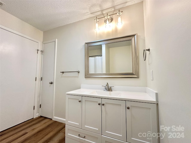 bathroom featuring vanity, wood-type flooring, and a textured ceiling