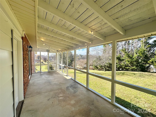 unfurnished sunroom with a healthy amount of sunlight and beam ceiling