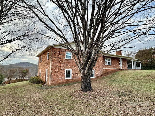 view of side of home with a sunroom, a mountain view, and a yard