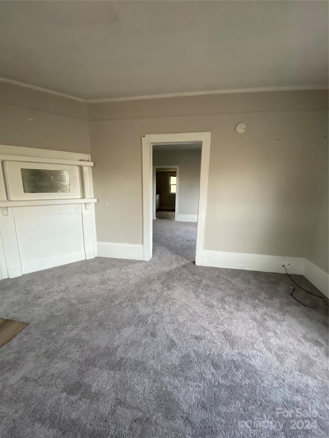 unfurnished living room featuring carpet and crown molding